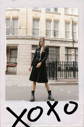 a lady in black pleated skirts with black jacket and ankle boots